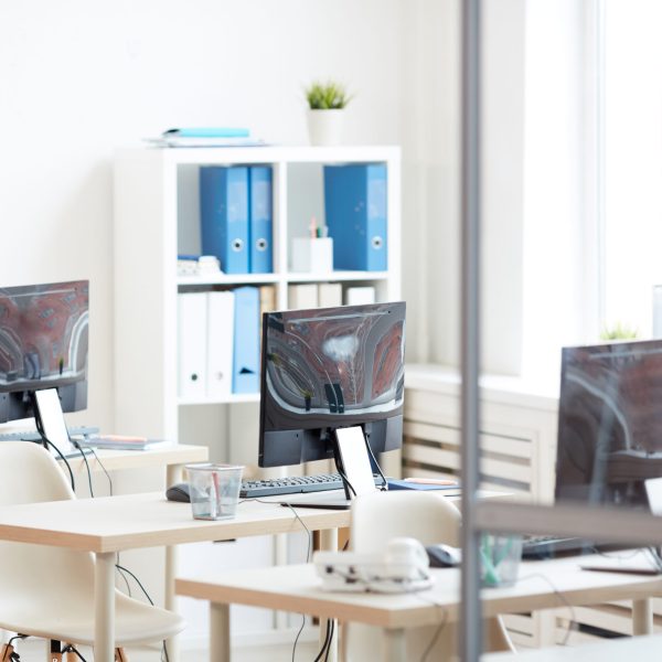 Background image of empty office desks in row set shot from behind glass door, copy space